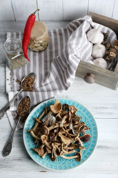 Gedroogde champignons in plaat met kruiden op houten tafel, bovenaanzicht — Stockfoto