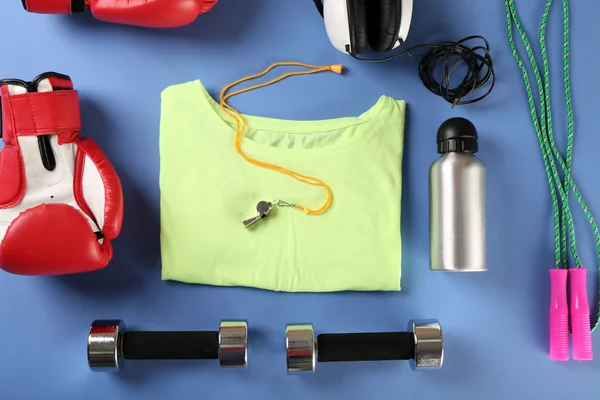 Sportuitrusting en t-shirt op kleurentabel, bovenaanzicht — Stockfoto