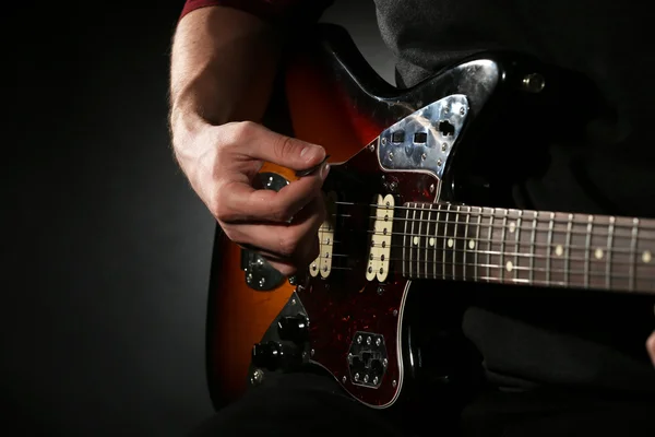 Jonge man spelen op elektrische gitaar op donkere achtergrond — Stockfoto