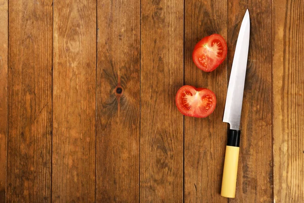 Moitiés de tomate avec couteau sur fond en bois — Photo