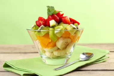 Tatlı yeşil zemin üzerine ahşap masa üzerinde cam daire içinde taze meyve