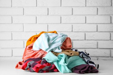 tuğla duvar arka plan üzerinde ahşap masa üzerinde farklı kıyafetler yığını