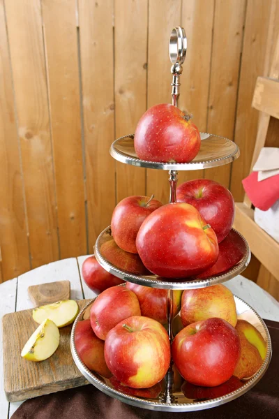 Sabrosas manzanas maduras en bandeja de servir en la mesa sobre fondo de madera —  Fotos de Stock