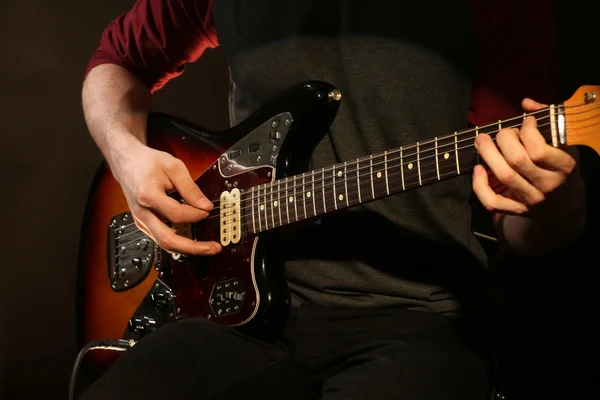 Mladý muž hraje na elektrickou kytaru na tmavém pozadí — Stock fotografie