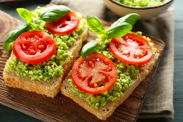 Vegansk smörgås med avokado och grönsaker på skärbräda, på trä bakgrund — Stockfoto