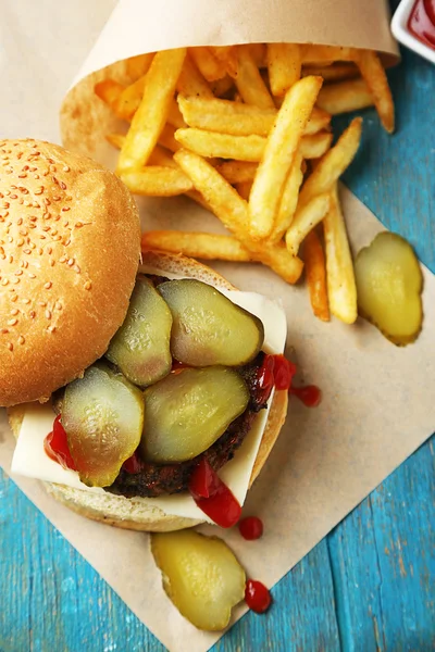 Νόστιμο burger και πατάτες τηγανιτές σε ξύλινο τραπέζι φόντο ανθυγιεινών τροφίμων ιδέα — Φωτογραφία Αρχείου