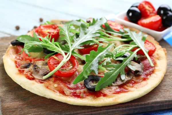 Смачна піца з овочами і руколою на обробній дошці на столі крупним планом — стокове фото