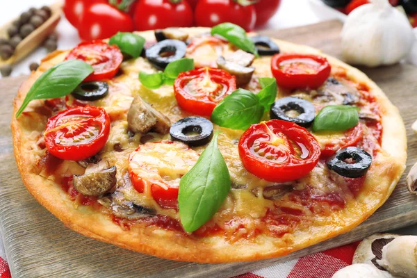 Gustosa pizza con verdure e basilico in tavola da vicino — Foto Stock