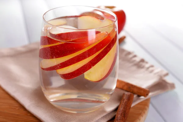 Glass of apple cider with fruits and cinnamon on table close up — Stock Photo, Image