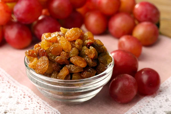 Raisins in bowl with grapes on table close up — Stock Photo, Image