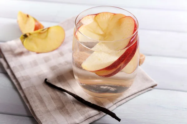 Glass of apple cider with fruits and vanilla stick on table close up — Stock Photo, Image