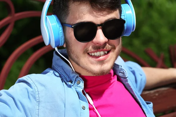 Homme avec écouteurs reposant sur le banc dans le parc — Photo