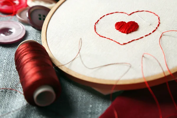 El aro de bordado con tela e hilos de coser rojos en la mesa de cerca — Foto de Stock