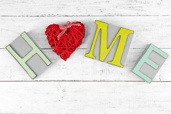 Lettere decorative che formano parola HOME con cuore decorativo su sfondo di legno — Foto Stock