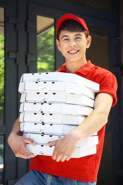 Jovem entregando caixa de pizza perto de casa — Fotografia de Stock