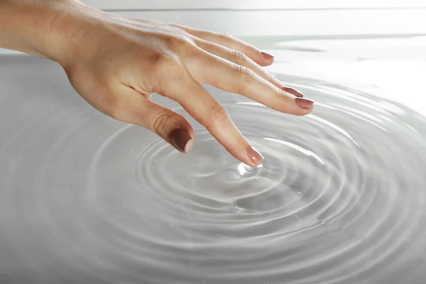 Main féminine touchant la surface de l'eau — Photo