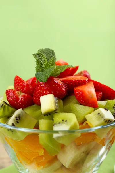 Postre de frutas frescas en platillo de vidrio sobre fondo verde — Foto de Stock