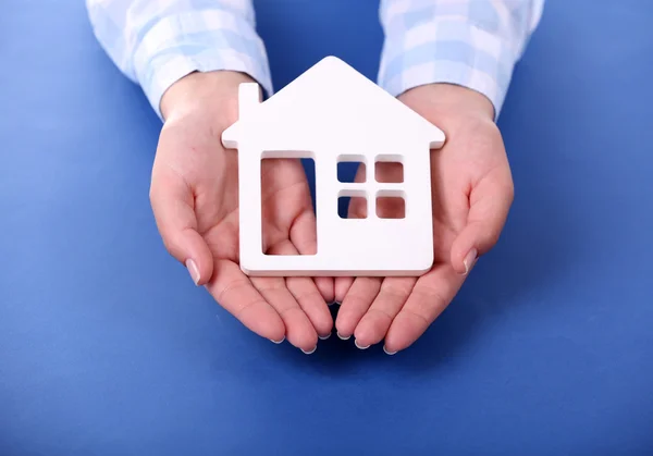 Weibliche Hände halten Haus auf farbigem Hintergrund — Stockfoto