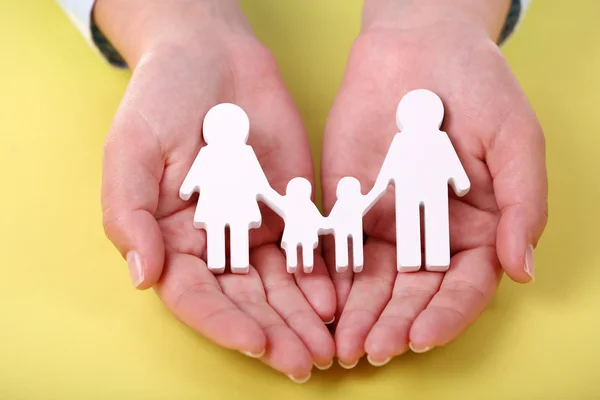 Female hands holding toy family on color background — Stock Photo, Image