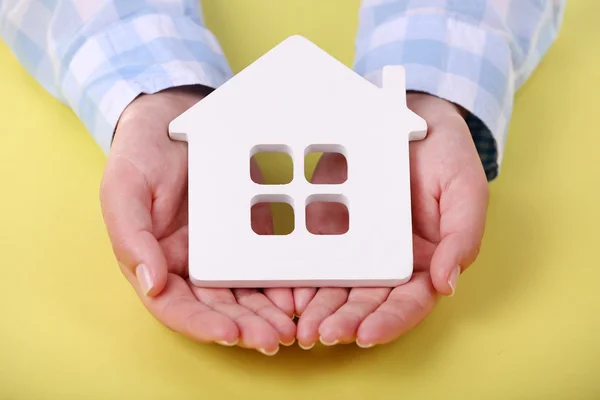 Female hands holding house on color background — Stock Photo, Image