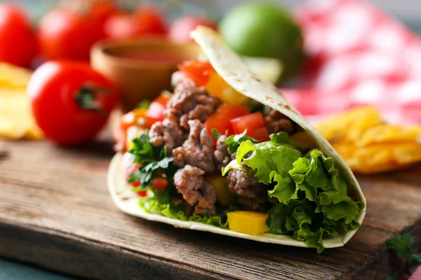 Домашнее говяжье буррито с овощами, картофельные чипсы на доске, на деревянном фоне — стоковое фото