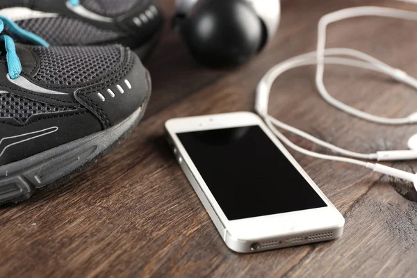 Sneakers and earphones on wooden table, closeup — Stock Photo, Image