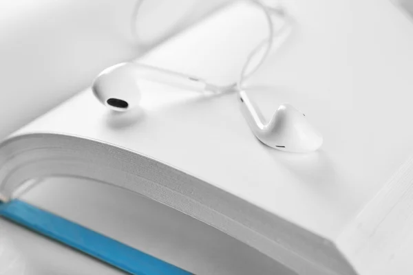 Earphones and book on table, closeup — Stock Photo, Image