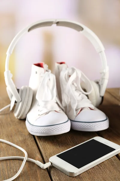 Zapatillas y auriculares en mesa de madera, primer plano — Foto de Stock