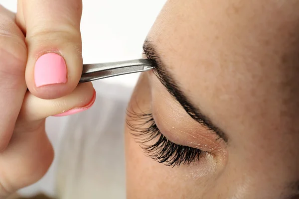 Jonge vrouw plukken wenkbrauwen met pincet sluiten — Stockfoto