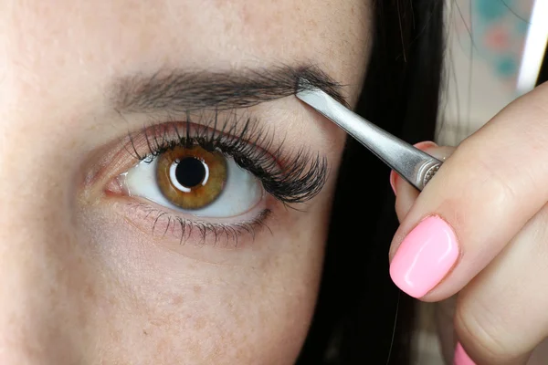 Mujer joven arrancando las cejas con pinzas de cerca — Foto de Stock