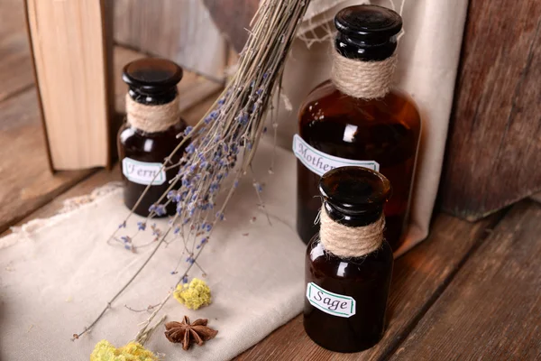 Dried herbs and bottles with tinctures on table close up — Stock Photo, Image