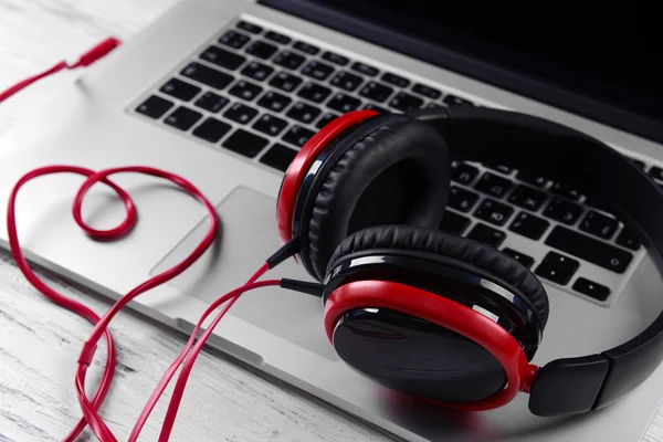 Fones de ouvido com laptop na mesa de perto — Fotografia de Stock