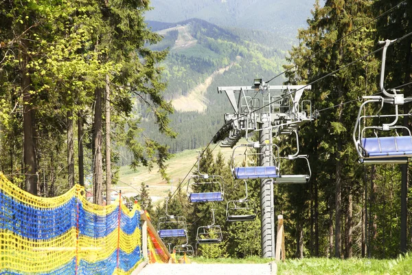 Sedačková lanovka nad zelenými stromy pozadí — Stock fotografie