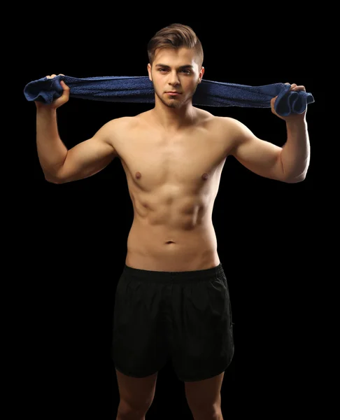 Spier jonge man houden handdoek op donkere achtergrond — Stockfoto