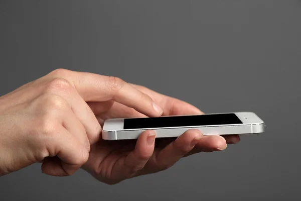 Hände halten Mobiltelefon auf grauem Hintergrund — Stockfoto