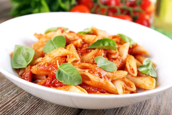 Pasta met tomatensaus en basilicum op tafel close-up — Stockfoto