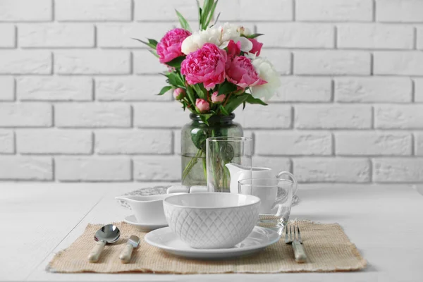 Hermosa mesa con flores en jarrón sobre fondo de pared de ladrillo —  Fotos de Stock