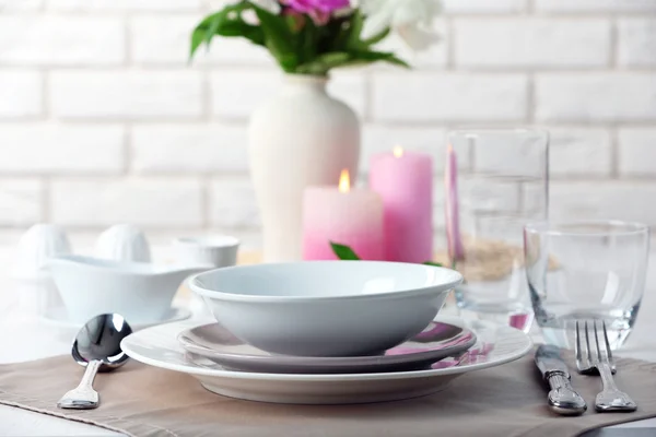 Cenário de mesa bonita com flores em vaso no fundo da parede de tijolo — Fotografia de Stock