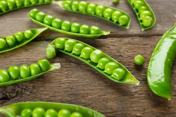 Frische grüne Erbsen auf Holzgrund — Stockfoto