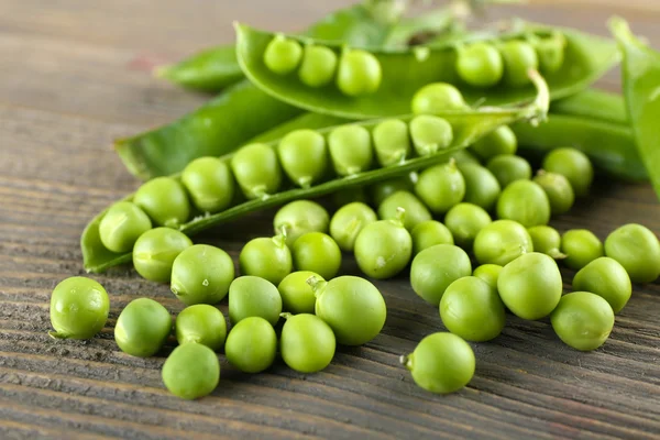 Frische grüne Erbsen auf Holztisch, Nahaufnahme — Stockfoto