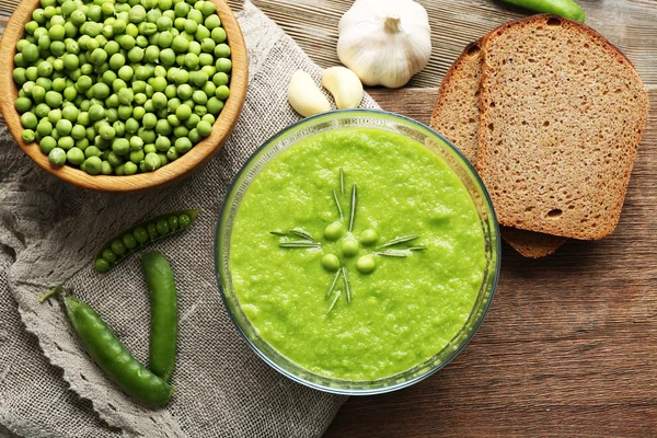 Green pea soup in glass bowl on wooden cutting board with sackcloth, top view — Stock Image Green pea soup in glass bowl on wooden cutting board with sackcloth, top view Royalty Free Stock Images
