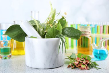 Harç, test tüpleri ve hapları, masada açık renkli otlar