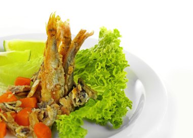 Marul ve üzerinde beyaz izole limon ile plaka üzerinde kızarmış küçük balık