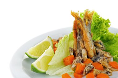 Marul ve üzerinde beyaz izole limon ile plaka üzerinde kızarmış küçük balık