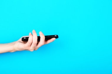 Cep telefonu üzerinde mavi arka plan kullanarak el