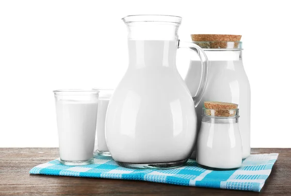 Pitcher, pots et verres de lait sur table en bois, sur fond blanc — Photo