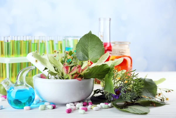 Herbs in mortar, test tubes and pills,  on table, on light background — Stock Photo, Image