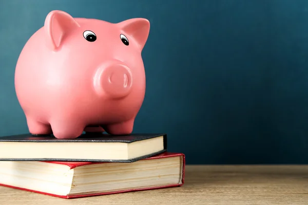 Salvadanaio con libri su sfondo lavagna — Foto Stock