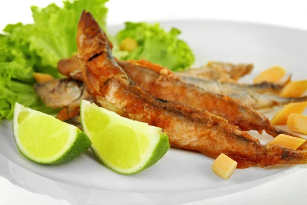 Pesce fritto piccolo con lattuga e lime sul piatto da vicino — Foto Stock