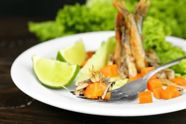 Смажена маленька риба з морквою і зеленню на столі крупним планом — стокове фото